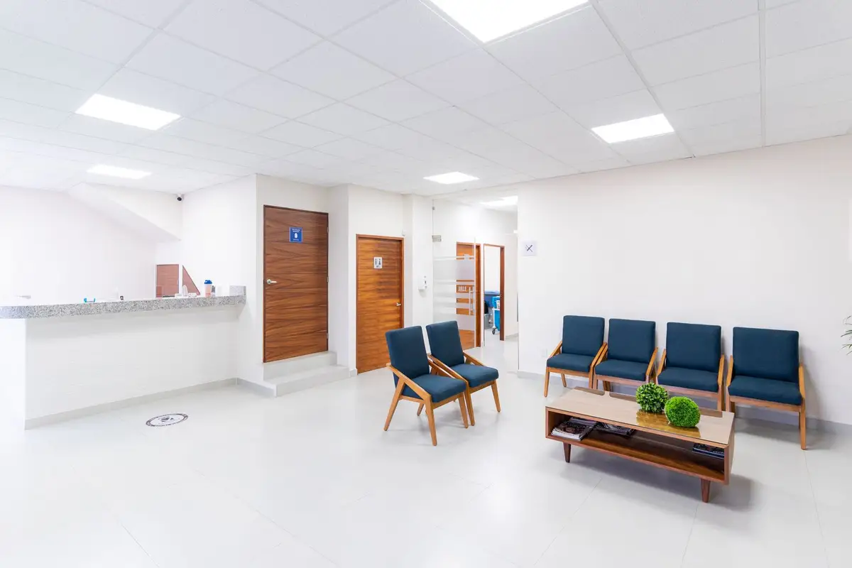 An empty, well-lit clinic waiting area with modern seating and a reception counter